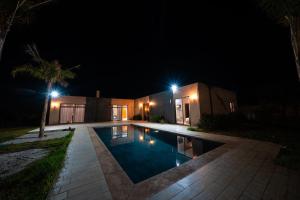 a swimming pool in front of a house at night at Viva La Villa in Marrakech