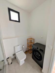 a bathroom with a toilet and a washing machine at Sea Beach Appartement in Tamarin +24 photos