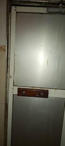 a close up of a metal door with a wooden handle at Super Paradise Hotel in Kampala +10 photos