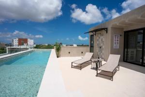 a patio with two chairs and a table next to a swimming pool at Nomad Studio Fast WiFi and Rooftop Pool in Cancún