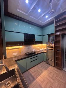 a large kitchen with blue cabinets and a sink at Sunita Kunj in Jhūsi