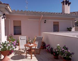 een patio met stoelen, een tafel en bloemen bij Casa Saba Lupino in Orosei