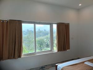 1 dormitorio con una gran ventana con cortinas marrones en Zira Homestay, en Munnar