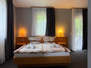a bedroom with a large bed with two windows at Sparta Hotel in Pottenstein