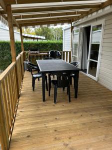 a patio with a table and chairs on a deck at Mobil-Home 3ch 8 pers - Les Charmettes K100 - Les Mathes in Les Mathes