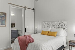 a bedroom with a white bed with two yellow pillows at Luxury Downtown Townhome - 120 Theater & Patio in Bentonville