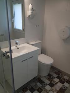 a white bathroom with a toilet and a sink at Habitacion en alojamiento turistico compartido con la amfitriona, estancias compartidas baño, terraza, cocina in Vilanova de Sau