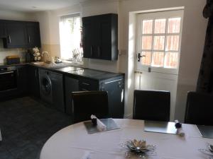 a kitchen with black cabinets and a table with chairs at Hamlet Cottage sleeps 3-4 Stratford upon Avon in Stratford-upon-Avon