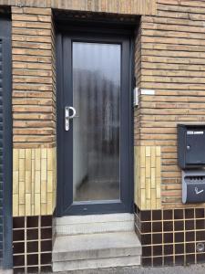 une porte noire sur le côté d'un bâtiment en briques dans l'établissement Bel-étage cosy 2 chambres proche Charleroi-Airport, à Charleroi