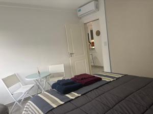 Cama en habitación con mesa y mesa en Departamento Castello -Viedma, en Viedma