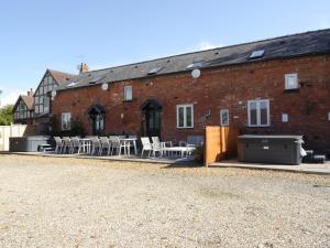 un bâtiment en briques avec des tables et des chaises devant lui dans l'établissement The Shakespeare Lodge - Sleeps up to 12 - 2 HOT TUBS, à Stratford-upon-Avon