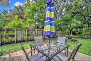a glass table and chairs with a umbrella at Blue Reverie - Downtown Cottage in Fort Lauderdale