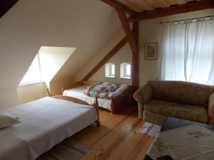 um quarto no sótão com 2 camas, um sofá e uma cadeira em Dom Gościnny Ogłuszka em Pilec