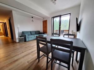 a living room with a table and chairs and a couch at Panorama Pine Retreat - Spacious 2-Bedroom Flat in Predeal