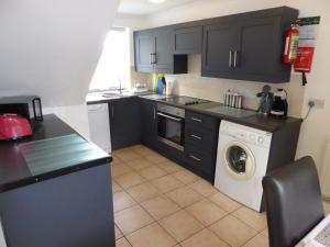 - une cuisine avec des armoires noires et un lave-linge dans l'établissement The Shakespeare Lodge - Sleeps up to 12 - 2 HOT TUBS, à Stratford-upon-Avon