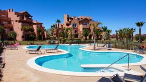 a swimming pool in a resort with chairs and buildings at Casa Menor - Mar Menor Golf in Torre-Pacheco