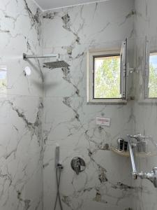 a white marble bathroom with a shower with a window at Lexhulo Room's in Domje
