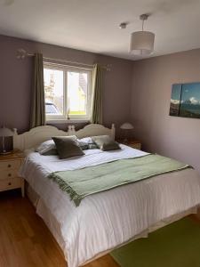 a bedroom with a large white bed with a window at Birch Cottage in Aviemore