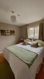a bedroom with a large white bed with a window at Birch Cottage in Aviemore