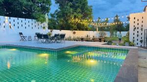 a swimming pool in a backyard with a table and chairs at Vela Pool Villa Hatyai in Sathani Khlong Rian
