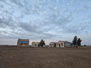 two buildings in the desert under a cloudy sky at The dune camp in Mhamid
