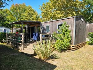 a wooden shed with a porch in a yard at Mobilhomme Privilège in Biscarrosse