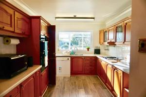a kitchen with red wooden cabinets and a window at The Peak View - Holmfirth in Cartworth