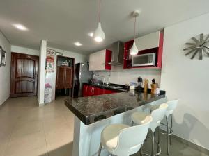 a kitchen with red cabinets and white bar stools at Exclusivo Apto Torres Del Lago in Cartagena de Indias