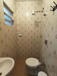 a bathroom with a white toilet and a sink at cantinho aconchegante in Praia Grande