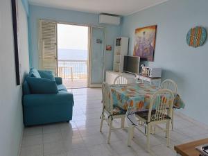a living room with a table and a blue couch at Mirone Apartment FRONTE MARE beachfront house in Roccalumera