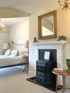 a bedroom with a bed and a fireplace with a mirror at Beautiful Georgian Country House - Norfolk in Dilham