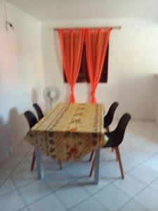 a dining room table with chairs and a window at F3 Meublé de Charme dans un écrin naturel en bas de Villa in Pointe-Noire