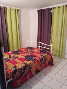 a bed with a colorful comforter in a bedroom at F3 Meublé de Charme dans un écrin naturel en bas de Villa in Pointe-Noire