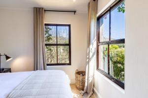 Un dormitorio con una cama y una ventana grande. en Franschhoek Charm, en Franschhoek