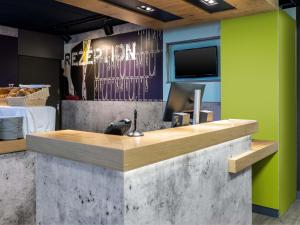 a restaurant with a reception counter with a tv at B&B HOTEL Saarbrücken-Ost in Saarbrücken