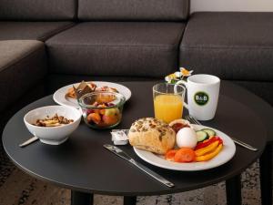 a table with a plate of breakfast foods and a glass of orange juice at B&B HOTEL Saarbrücken-Ost in Saarbrücken