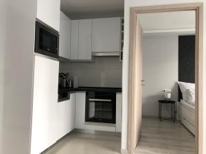 une petite cuisine avec des placards blancs et une télévision dans l'établissement Luca Apartman, à Keszthely