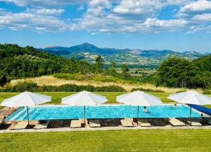 a group of white umbrellas and a swimming pool at La Capella in Gubbio
