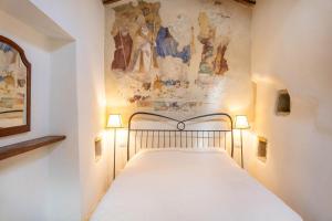 a bed in a room with a painting on the wall at La Capella in Gubbio