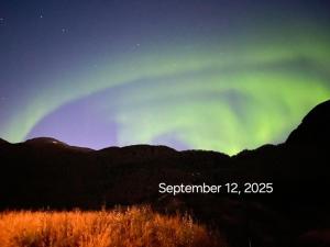 an aurora in the sky over a mountain at Fjord & Flame in Tromsø