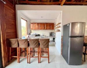 a kitchen with a stainless steel refrigerator and some chairs at Casa Iguana hotel boutique in El Cuyo