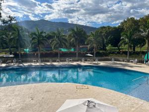 a large swimming pool with chairs and mountains in the background at Apartasol vacacional in Santa Fe de Antioquia
