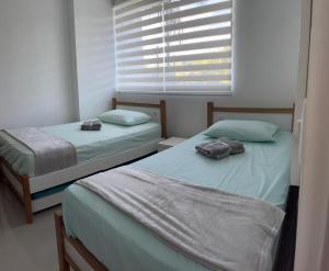 two twin beds in a room with a window at Apartasol vacacional in Santa Fe de Antioquia +13 photos