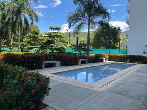 a swimming pool in a park with trees and bushes at Apartasol vacacional in Santa Fe de Antioquia