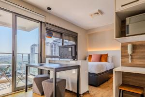 a bedroom with a bed and a desk with a television at Vossa Bossa Vila Madalena in São Paulo
