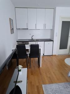 サラエボにあるMia Apartmentの白いキャビネットとテーブルと椅子のあるキッチン +6枚の写真