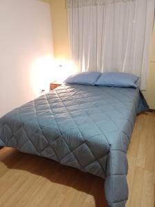 a bed with a blue comforter in a bedroom at El Refugio al Norte del Fin del Mundo A in Río Grande