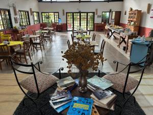 a dining room with tables and chairs and a table with books at Pousada Chalés da Estalagem in São Bento do Sapucaí