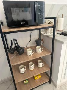 a shelf with four coffee cups and a microwave at Blue'ming Sousse in Sousse