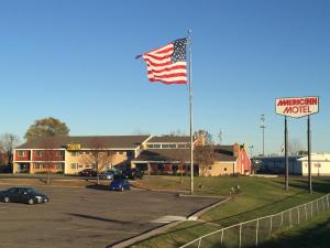 een Amerikaanse vlag op een paal op een parkeerplaats bij AmericInn Motel - Monticello in Monticello